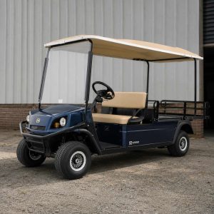 Golfette Ezgo bleu avec toit et sellerie beiges, dans un entrepôt
