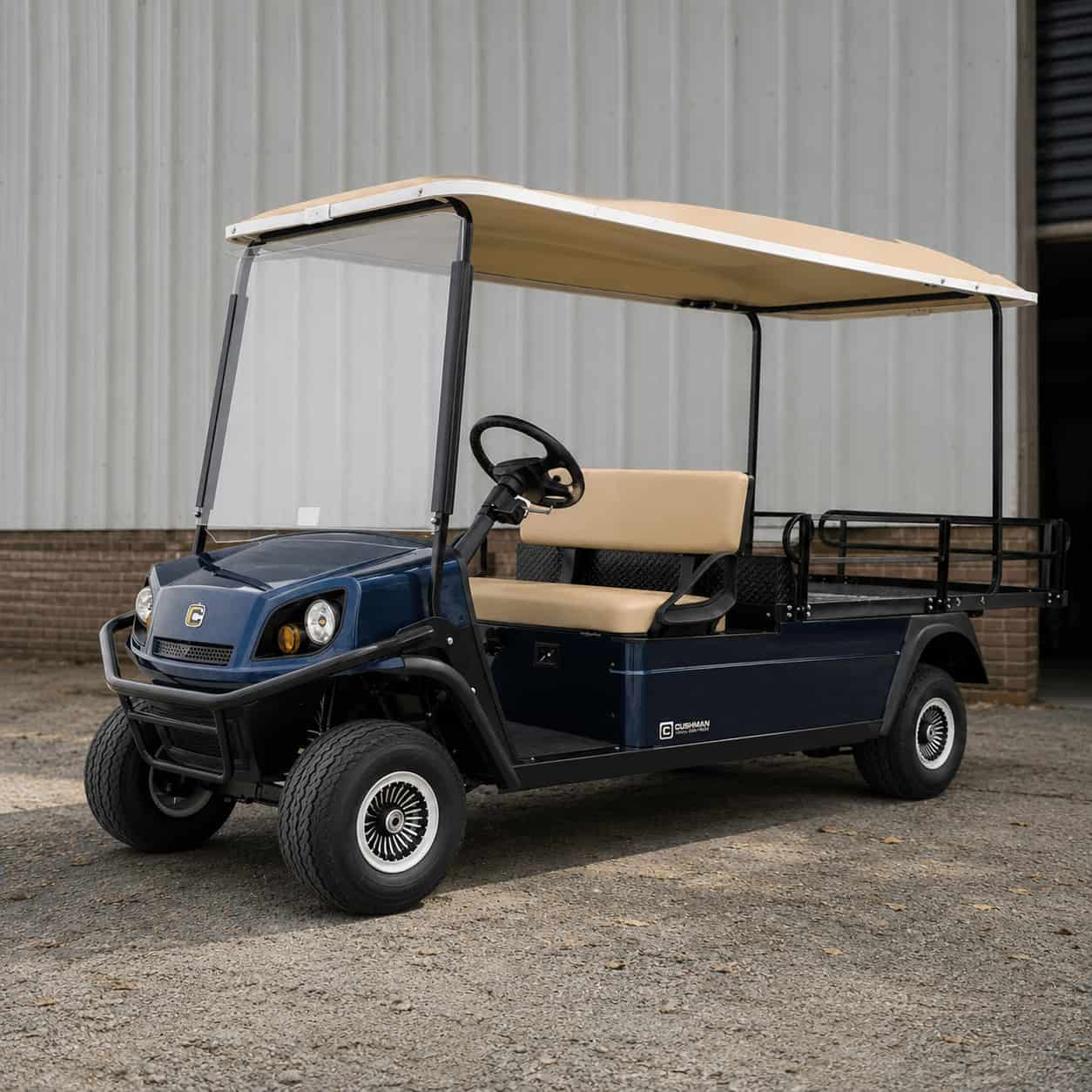 Golfette Ezgo bleu avec toit et sellerie beiges, dans un entrepôt