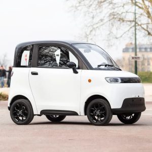 La voiture sans permis Simplici S1 blanche dans un parking de jour