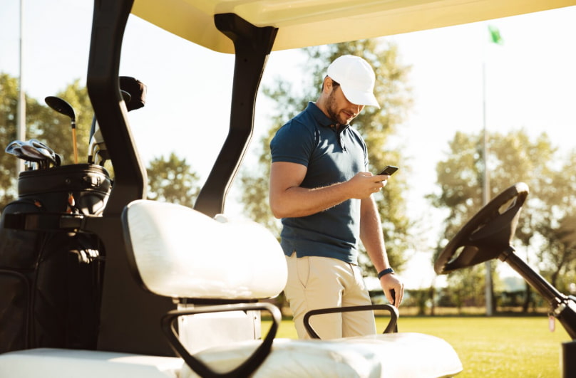 Golfeur avec casquette près de sa voiturette de golf